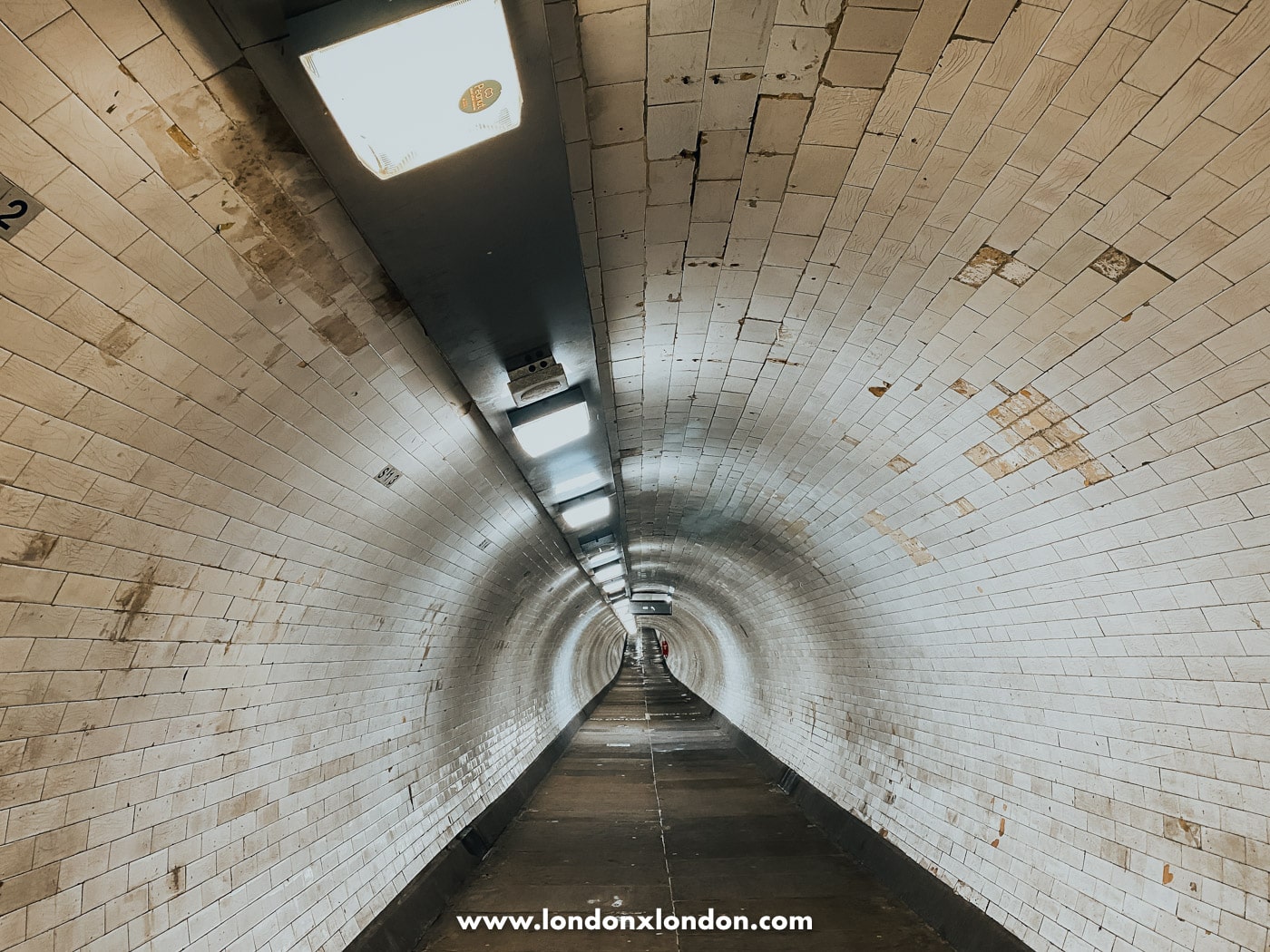 The empty Greenwich Foot Tunnel, tiled walls curving away into the distance