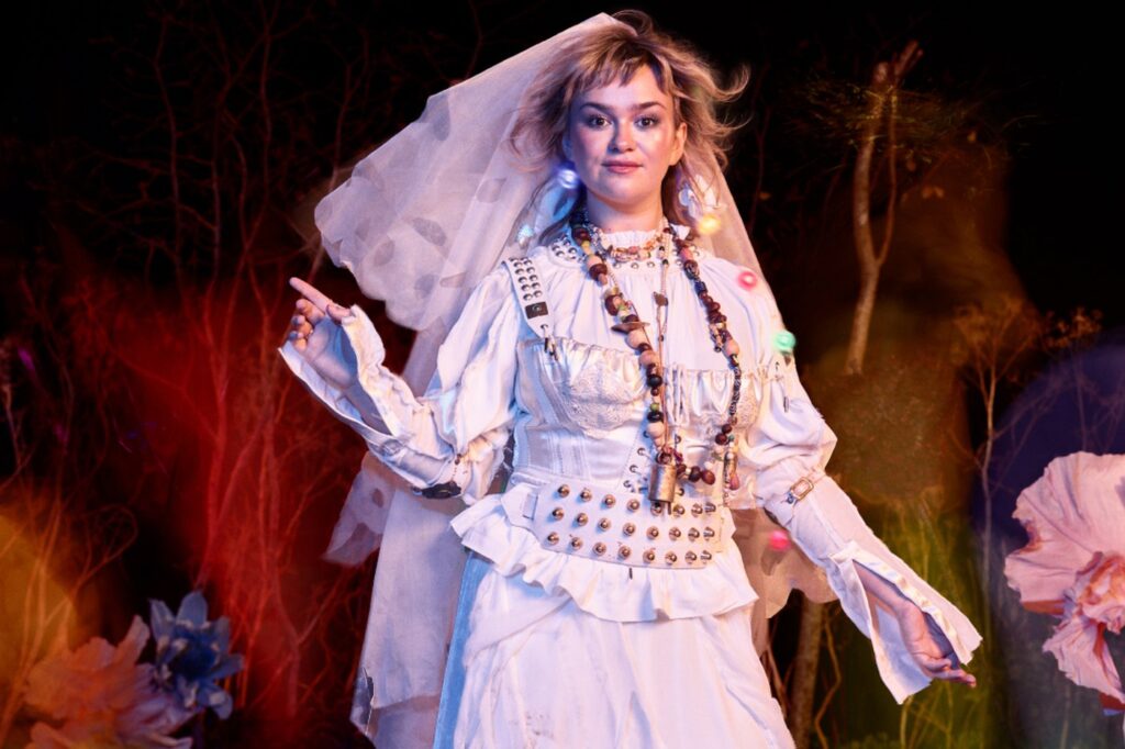 Rosalind in a festival-style wedding dress and fairy lights in the Forest of Arden, Shakespeare's Globe's 2026 production of As You Like It