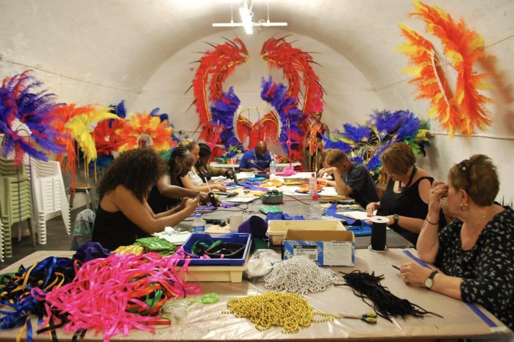 People making colourful feathered Carnival headdresses at a workshop table