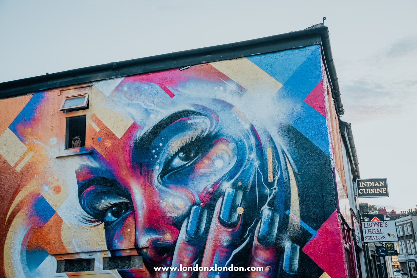 A Mr Cenz mural in blue, pink and orange on a building in Crystal Palace