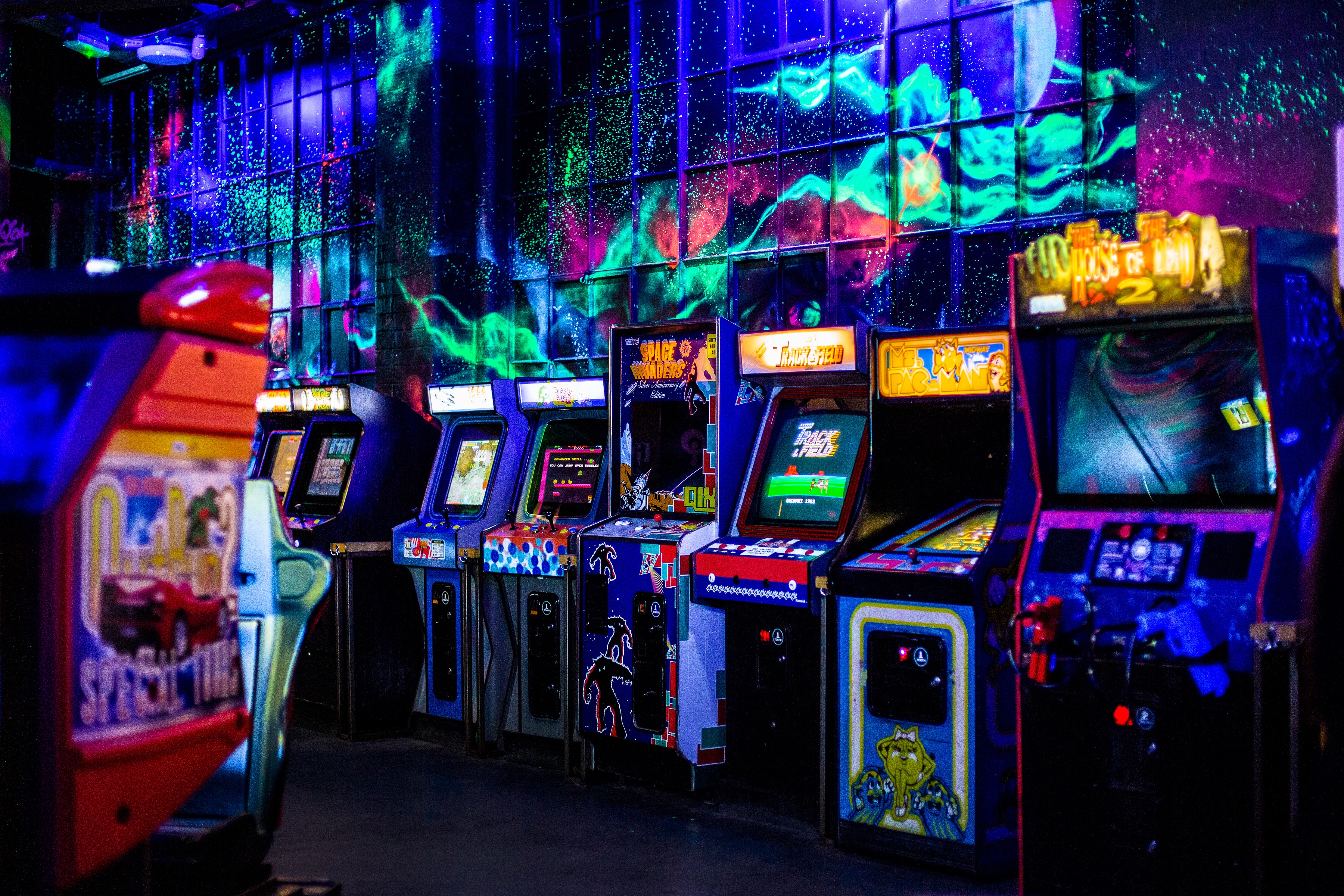 A wall of retro arcade cabinets lit up in neon at NQ64