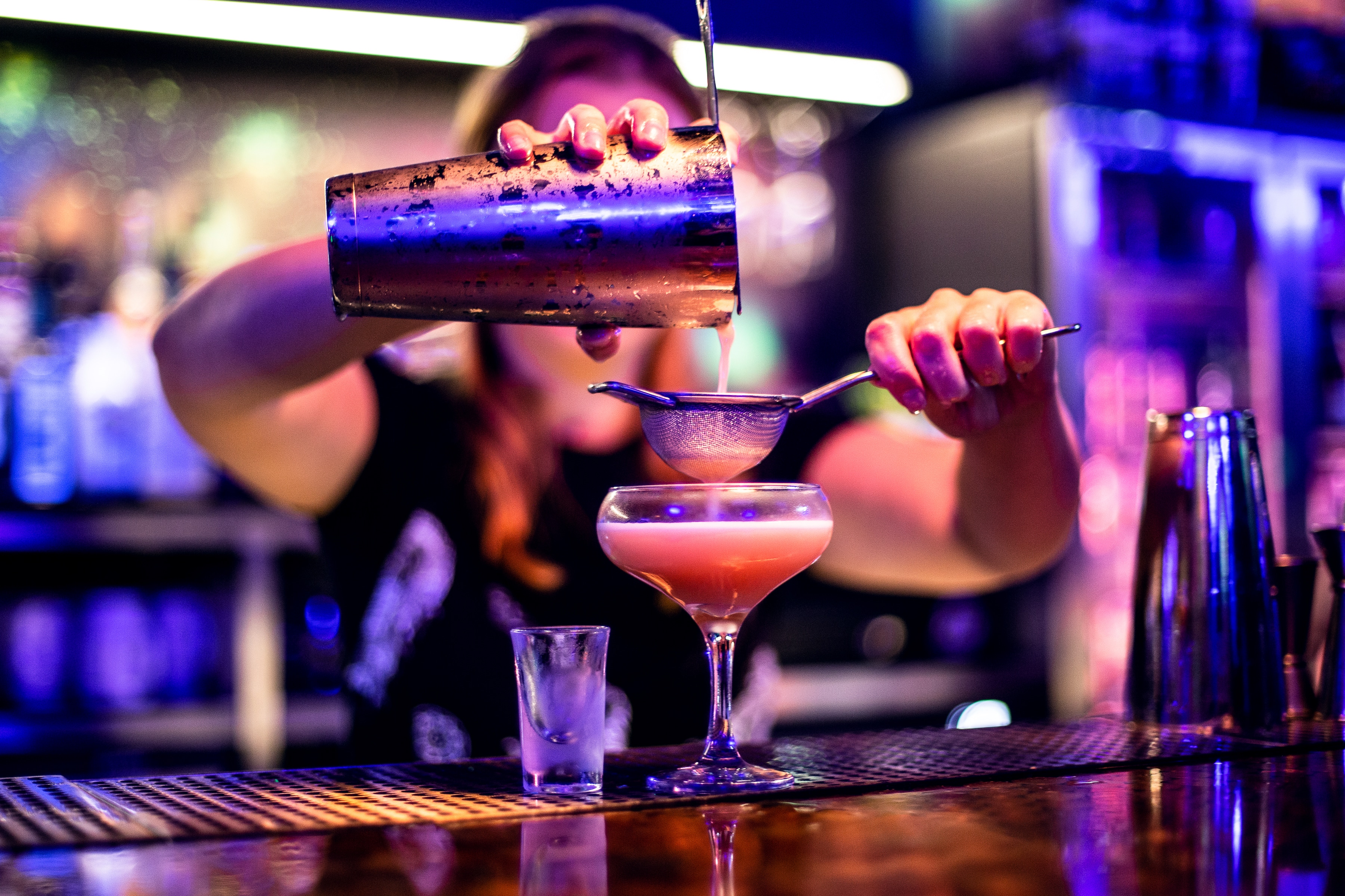 A bartender straining an arcade-inspired cocktail at NQ64