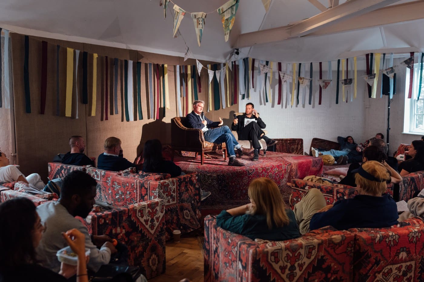 The audience at a Sunday Papers Live talk, seated on kilim-covered platforms