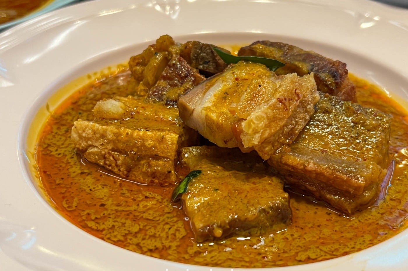 A pork rib and crispy pork belly curry at Speedboat Bar, turmeric-gold with curry leaf