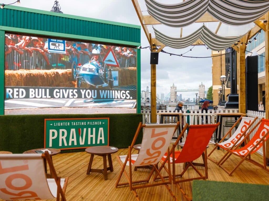 Deckchairs facing the big screen at The Clubhouse, with Tower Bridge visible on the river behind