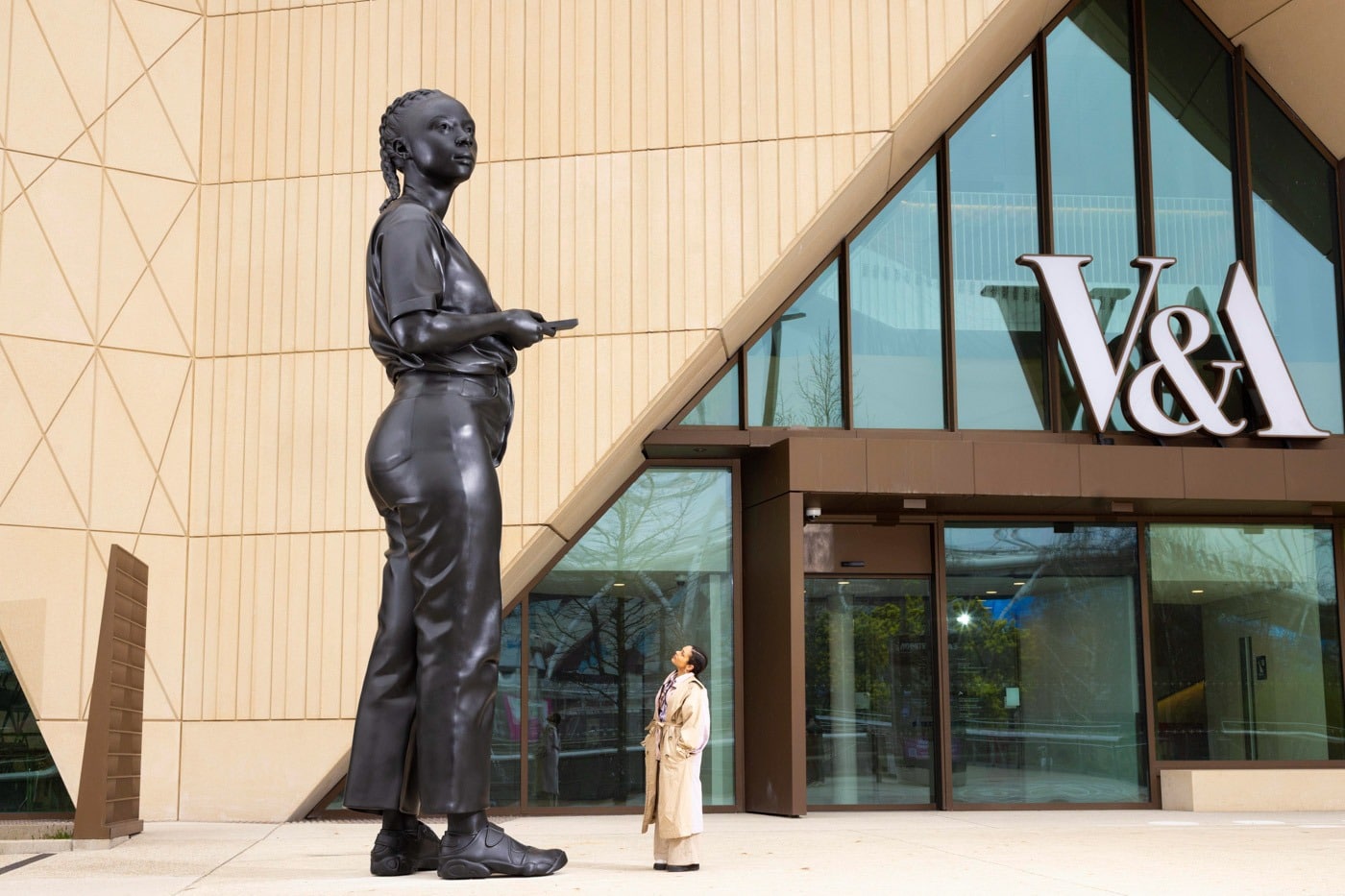 Thomas J Price's 5.5-metre bronze sculpture A Place Beyond outside the V&A East Storehouse, with a visitor standing beside it for scale