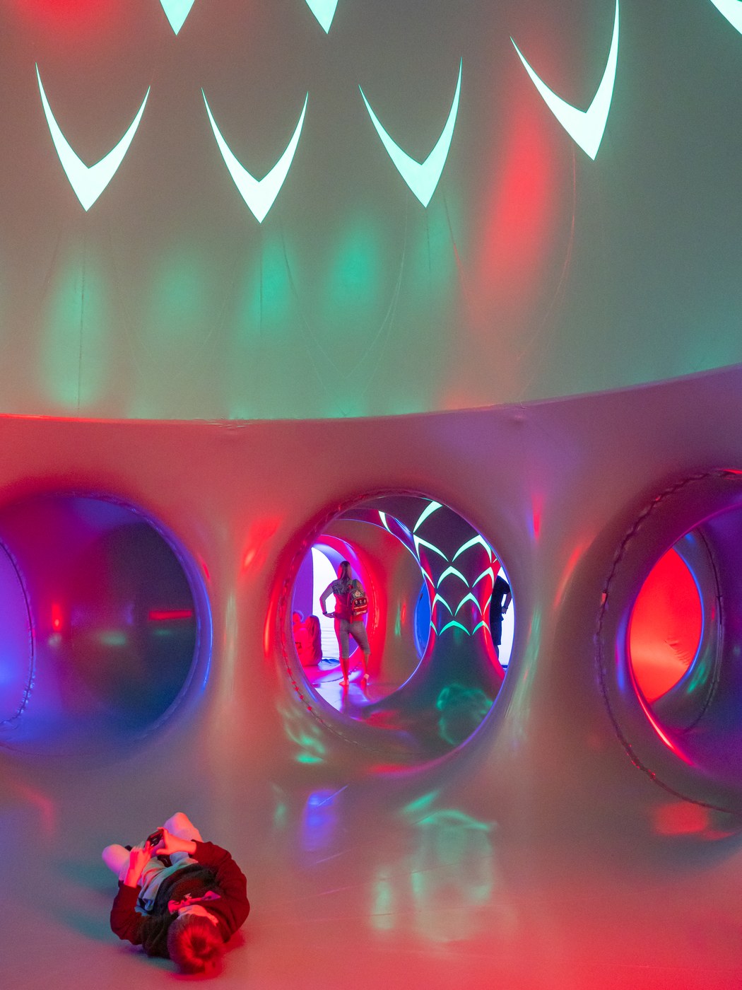 A visitor lying on the floor looking up at the patterned dome of the ARBORIALIS Luminarium