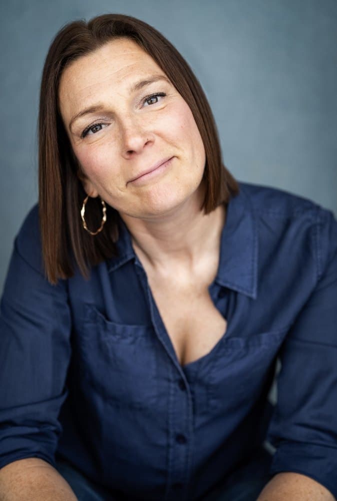 Charlotte Arrowsmith, director of Hear Art's Constellations, photographed in a navy shirt against a grey background