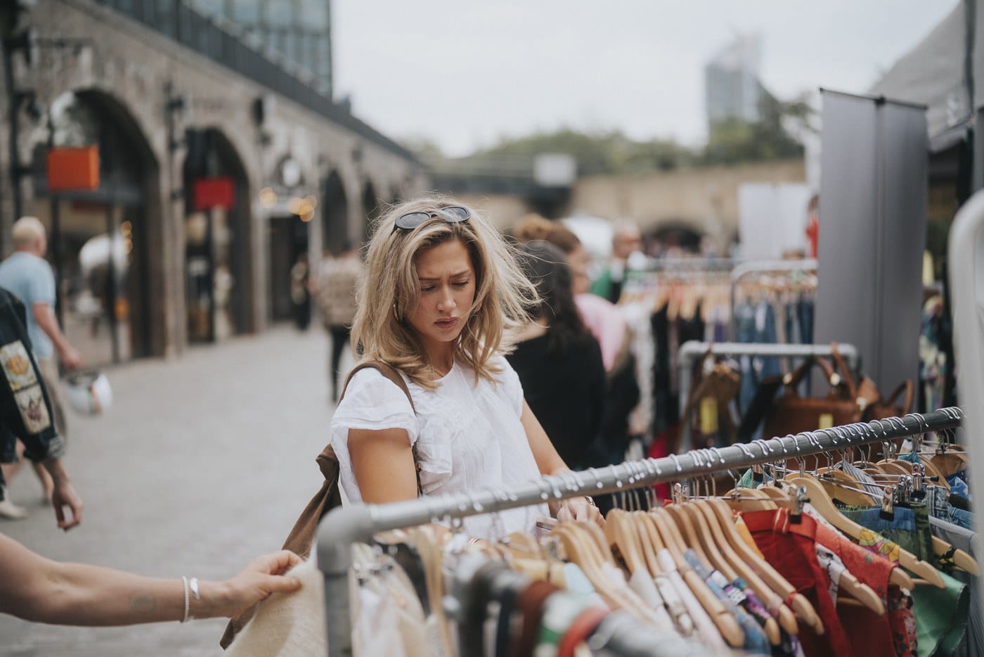 A woman looking through a rail of vintage clothing in the arches at Coal Drops Yard