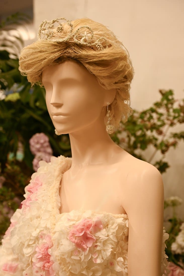 Close view of a tiara made from tiny white flowers set into a wig spun from raffia, with drop earrings made of dried blooms
