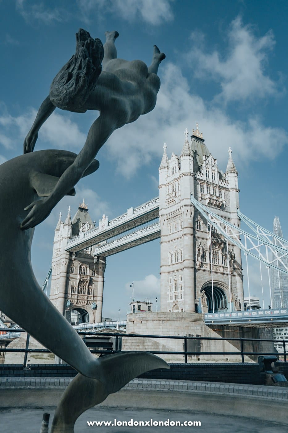 Girl with a Dolphin fountain and its basin at St Katharine Docks with Tower Bridge behind
