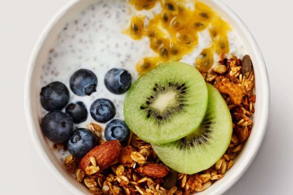 A Joe and the Juice chia pudding breakfast bowl with blueberries, passion fruit, kiwi slices and granola, shot from above