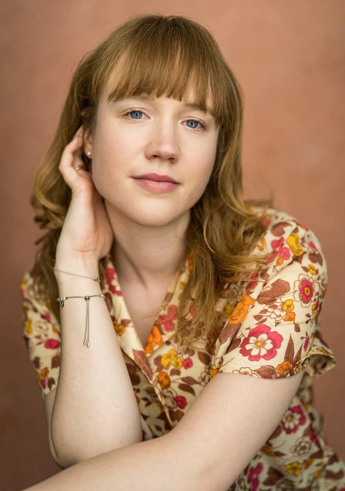 Actor Kitty Devlin, who plays Marianne in Constellations, photographed in a floral top against a terracotta background
