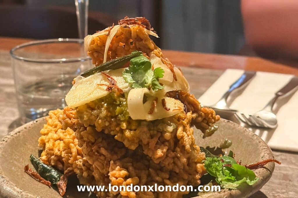 Biryani rice crackers at Kolae, stacked high in a stone bowl under crispy fried shallots and coriander