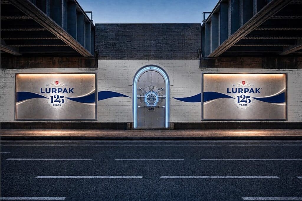 A steel bank-vault door lit in blue neon under a railway bridge, flanked by two illuminated Lurpak 125 Years billboards