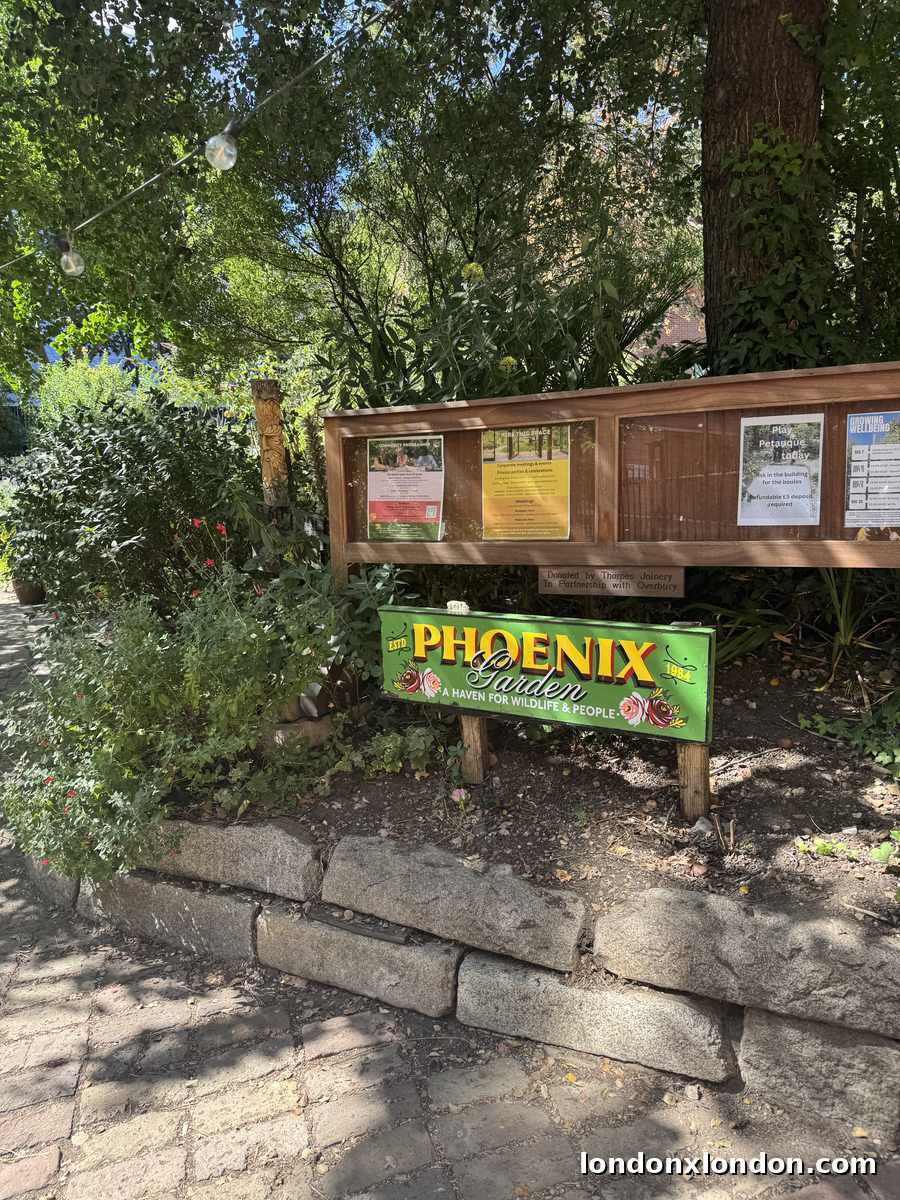 The garden noticeboard listing community programmes, petanque and venue hire, with the timber community building and planting behind