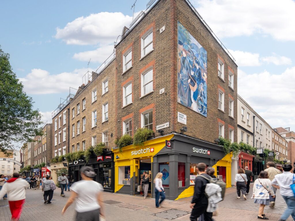 Renoir's The Umbrellas painted as a five-metre mural high on the brick corner of Carnaby Street and Ganton Street in London, with shoppers passing below