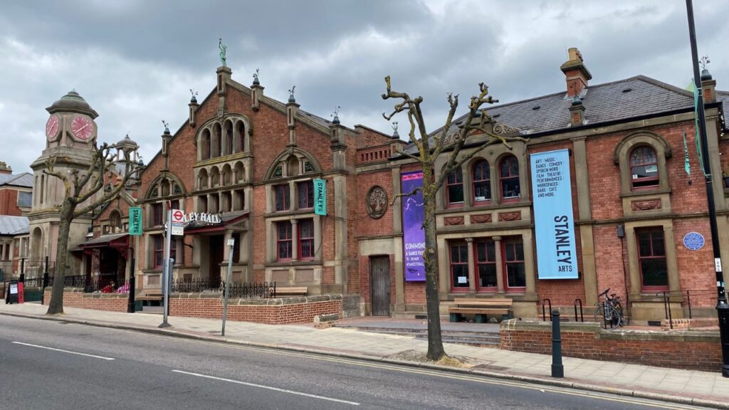 The red-brick Edwardian frontage of Stanley Arts on South Norwood Hill, with its pink-faced clock tower and Stanley Arts banners