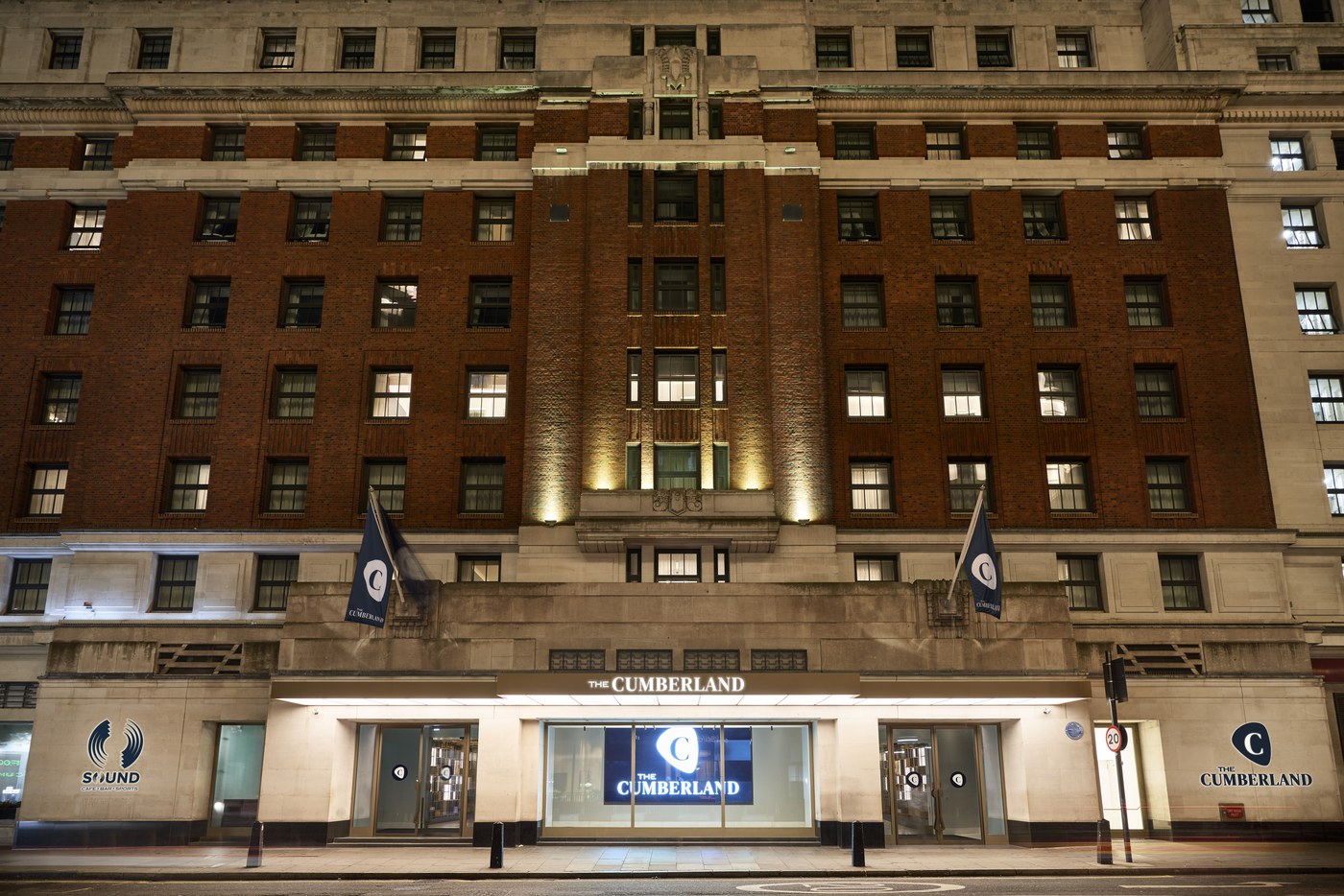 The art deco brick facade of The Cumberland hotel at Marble Arch, lit at night
