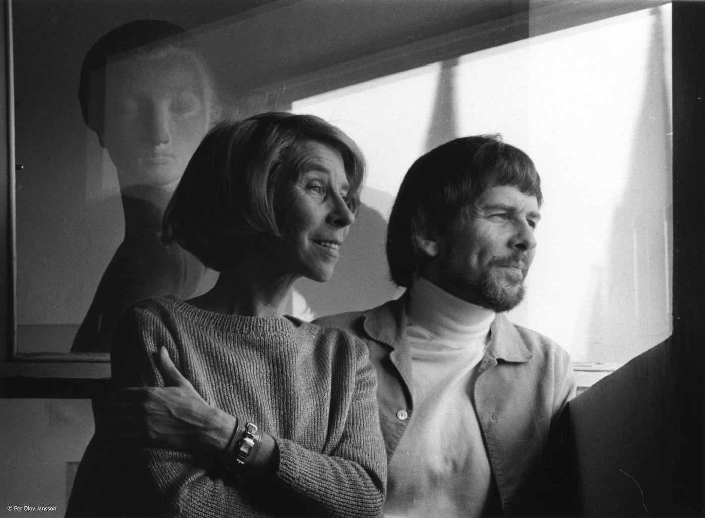 Tove Jansson and her brother Per Olov Jansson at a window, her reflection visible in the glass behind them