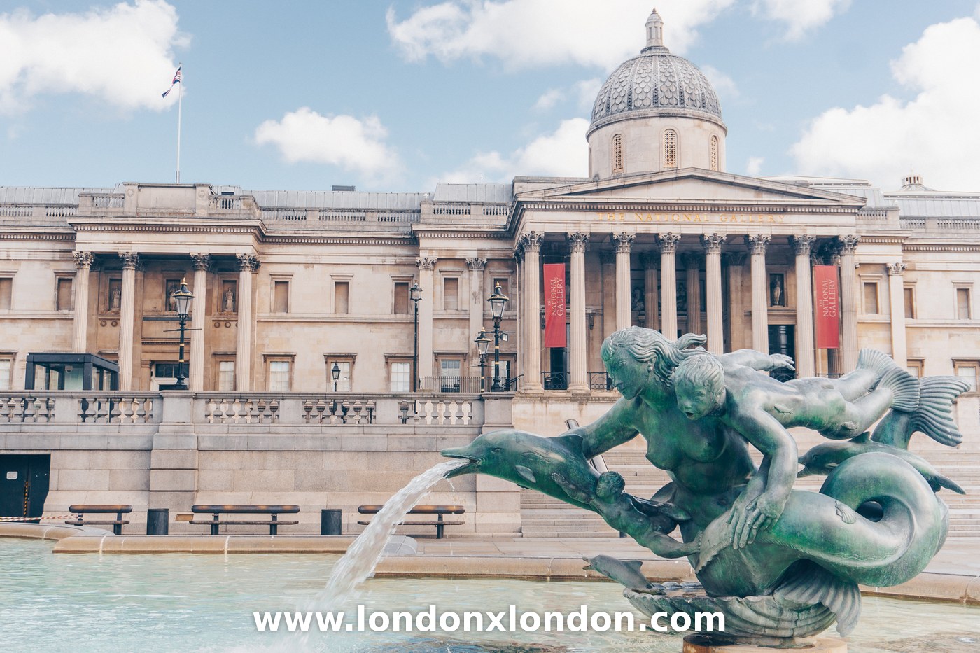 Bronze triton and mermaid sculpture spouting water from a dolphin's mouth in a Trafalgar Square fountain